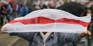 Eine Frau hält sich eine rot-weiße Fahne vor ihr Gesicht