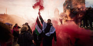 Teilnehmer einer Pro-Palästina-Kundgebung auf der Straße Unter den Linden zünden Pyrotechnik.
