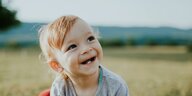 Ein lachendes Kleinkind mit den ersten zwei Zähnen.
