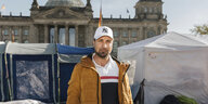 Ein Mann steht vor Zelten auf der Wiese vor dem Deutschen Bundestages