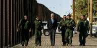 Joe Biden läuft mit Grenzbeamten an einem Zaun entlang