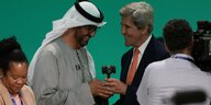 Konferenzpräsident Sultan al-Jaber mit dem US-Klimabeauftragten John Kerry, sie halten einen Hammer in der Hand