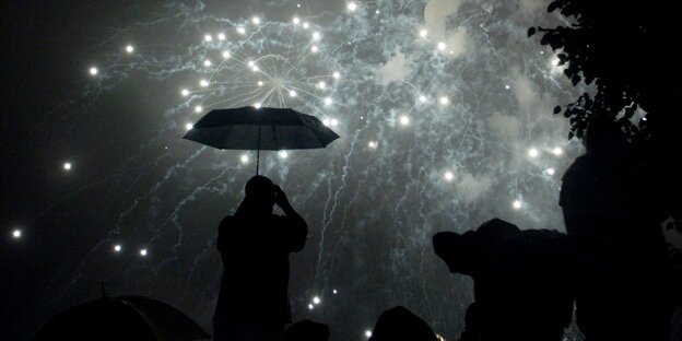 Mann mit Schirm unter Feuerwerk