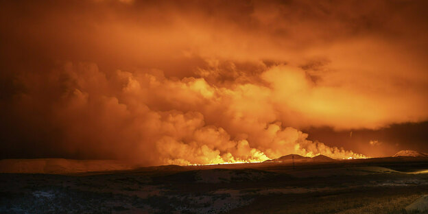 Rauch kommt aus einem Vulkan vor einem rot erleuchteten Himmel