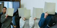 Fünf Personenverdecken ihr Gesicht mit Mappen