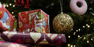Eingepackte Geschenke liegen unter einem geschmückten Weihnachtsbaum.