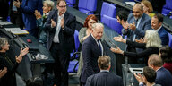 Jürgen Trittin geht zwischen applaudierenden Abgeordneten im Bundestagsplenum