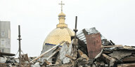 Gebüudetrümmer, dahinter die goldene Kuppel einer orthodoxen Kirche