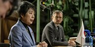Japans Außenministerin sitzt mit gefalteten Händen an einem Tisch und spricht zu Medien, vor sich eine kleine japanische Flagge