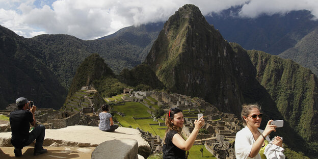Touristinnen nehmen sich mit Mobilfon auf mit der Zitadelle von Machu Picchu