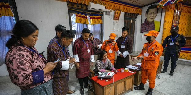 Wahlhelfer in Bhutan entsiegeln unter dem Portrait des Königs eine eletronische Wahlmaschine, um die Stimmen auszuzählen.