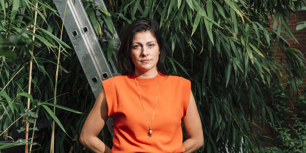 Effekbewusst: Katrin Gebbe in orangem Shirt vor dem Grün von Pflanzen