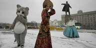 Verschiedene Personen in Kostümen vor einer Lenin-Statue