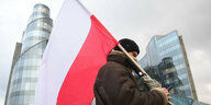 Ein Mann hält eine polnische Flagge.