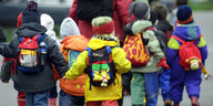 Kindergarten-Kinder in bunter Regenkleidung und Rucksäcken unterwegs