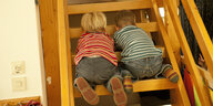 Zwei Kinder hocken auf einer Leiter und gucken durch die Stufen