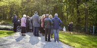Trauernde bei Urnenbeisetzung auf Rasenfriedhof