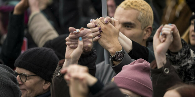 Teilnehmer einer Demonstration halten sich an den Händen.