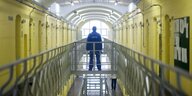 Justizbeamter steht auf einer Brücke in einem Gefängnistrakt