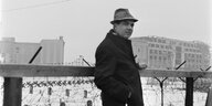 ein Mann im Mantel und mit Hut am Todesstreifen in Berlin 1963, an der Hand hängt eine Fotokamera