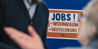 8687215 Beschreibung Auf der Jobmesse «FuTog Berlin» (FutureTogether Berlin) für Geflüchtete werden unter anderem Jobs mit Wohnraum und Deutschkurs angeboten. Das zeigt ein Plakat, dass auf dem Foto zu sehen ist.