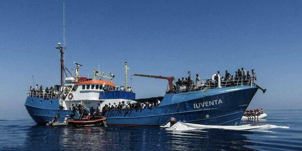 Gerettete Flüchtlinge sitzen an Bord eines Schiffes.
