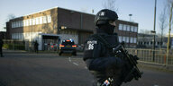 Ein uniformierter und schwer bewaffneter Polizist vor einem gerichtsgebäude in Amsterdam