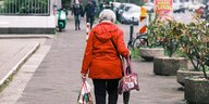Eine Rentnerin trägt Einkaufstaschen