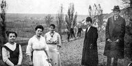 Franz Kafka mit Hut und Mantel (re) steht lächelnd mit vier Frauen auf einer Wiese