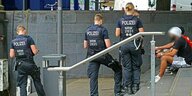 Drei PolizistInnen stehen auf einer Treppe von jungen Leuten, die kontrolliert werden