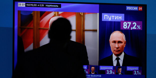 Vor einem Fernseher verfolgt eine Person die Ergebnisse der Wahlen in Russland.