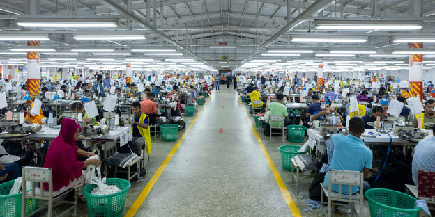 Menschen arbeiten an Nähmaschinen in einer Textilfabrik