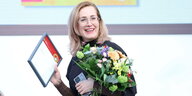 Barbi Markovic mit Blumenstrauß und Auszeichnung