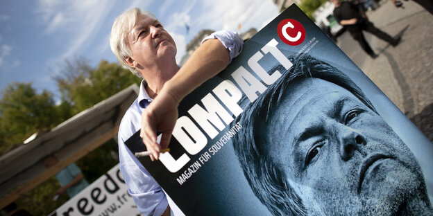 Jürgen Elsässer posiert mit einem Plakat des Compact-Magazins