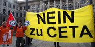 Menschen auf einem Platz mit einem Transparent, auf dem "Nein zu Ceta" steht