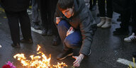 Ein Mann kniet an nieder und zündet eine Kerze zum Gedenken an die Terroropfer in Russland an