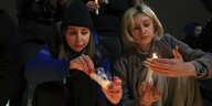 Zwei Frauen zünden Kerzen an nach dem Terroranschlag in Moskau