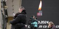 Menschen weinen und umarmen sich vor der brennenden Kerze auf einem Bildschirm