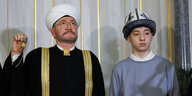 Islam Khalilov steht in traditioneller Kleidung bei einer Zeremonie steht neben einem Mitglied des Rates der Muftis