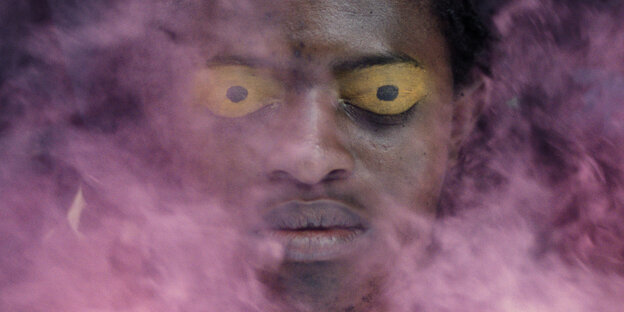 Ein Gesicht mit maskenhaften gelben Augen wird von rosa Rauch teilweise überdeckt