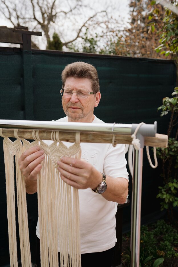 Manfred Hall is working on a macrame work.