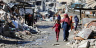 Eine Frau und ein Mädchen laufen durch ein völlig zerstörtes Viertel in Gaza.