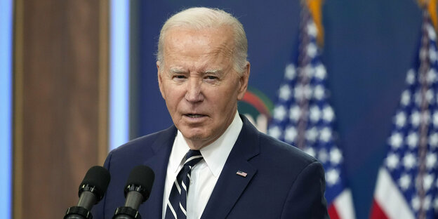 Joe Biden is standing at the speaker's desk in a suit
