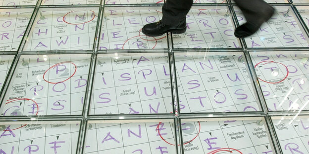 Ein Mensch läuft auf einem symbolischen, riesigen Kreuzworträtsel