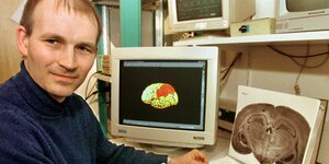 Der Neurobiologe Andreas Kreiter 1998 in seinem Labor in der Bremer Uni; auf dem Computerbildschirm hinter ihm ist gerade die Abbildung eines Gehirns zu sehen, bei dem ein Teil eingefärbt ist. Auch der Block in seinen Händen zeigt einen Gehirnquerschnitt