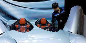Ein Mann reinigt ein Auto auf der Messe Auto China 2024 in Peking