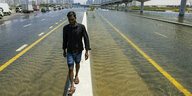 Ein Mann geht entlang einer Straßensperre inmitten von Hochwasser, das durch starken Regen verursacht wurde.