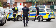 Mehrere Streifenwagen stehen auf einer Straße in Nienburg. Drei uniformierte Polizisten bewegen sich hinter einer Absperrung.