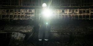 Eine Person mit Taschenlampe in einem dunklen Kontrollraum
