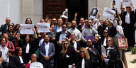 Protestierende stehen mit Schildern in den Händen auf der Treppe vom Justiz Palast in Tunis.